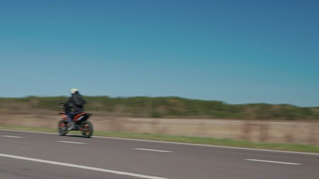 Professional stunt rider riding on rear wheel on a country road, slow motion
