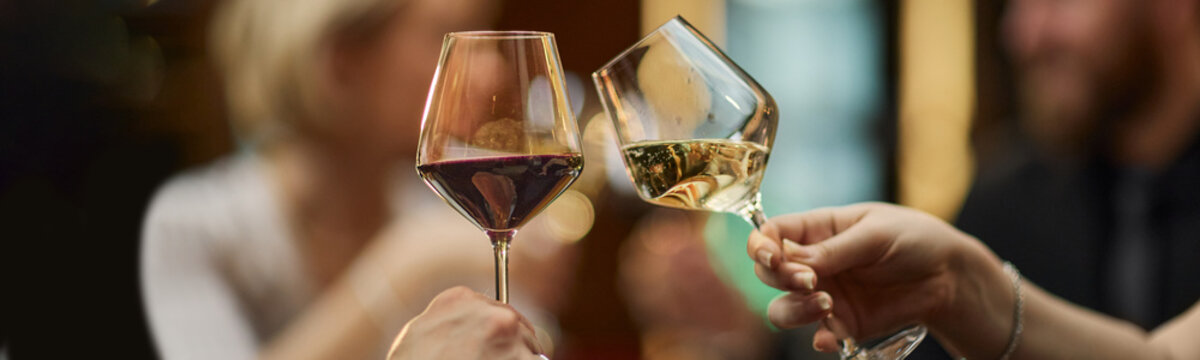 Header of adult hands clinking red and wine glasses during social gathering, signaling celebration and hospitality. Supporting restaurant, event, nightlife, beverage marketing