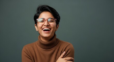 Fototapeta premium A smiling person with glasses and a brown turtleneck sweater against a gray background portrait view