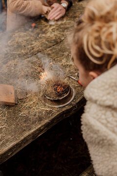 Child learning to make fire outdoors with natural materials