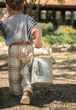 Cute Kid Carrying Vintage Metal Watering Can in Garden