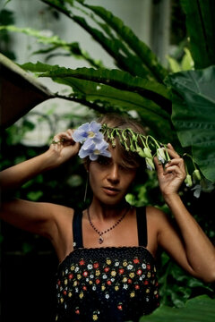 Woman holding tropical flowers over head in garden, Bali, Indonesia