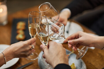 Close up of adult friends clinking champagne glasses during restaurant meal, celebrating social gathering and shared success. Suitable for hospitality marketing, event promotion, lifestyle branding © Seventyfour