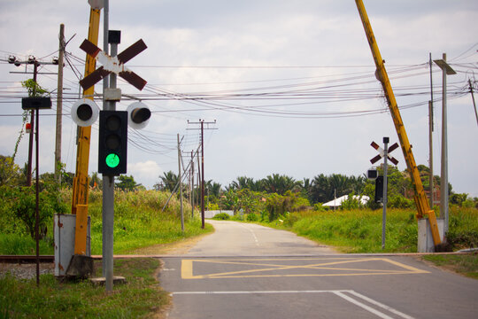 An empty railway level crossing with green signal and open barriers