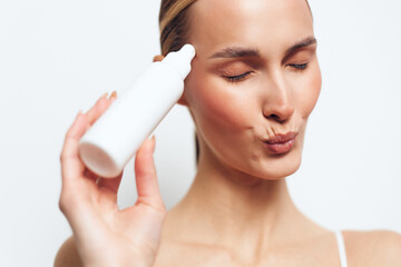 Woman skincare beauty, cream bottle applying, close up, eyes closed self care hygiene, calm expression, soft studio light, clean white background, minimalist portrait, skincare routine