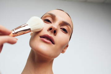 Woman in a beauty spa gets facial makeup applied with a soft brush, calm closeup of her face and skincare, clean background, professional cosmetic treatment care concept