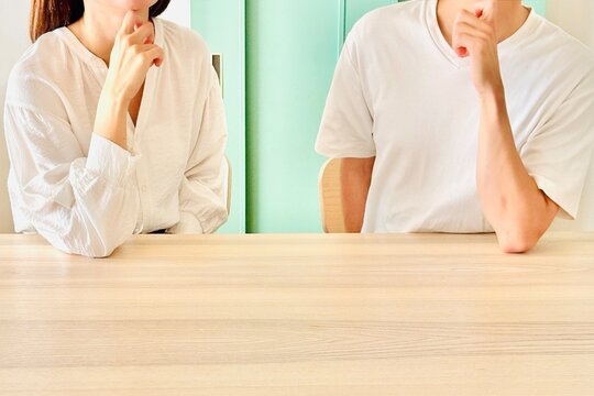顎に手を当てて一緒に考える若い夫婦