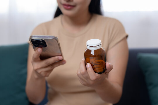 women holding medicine bottle and using smartphone to check dosage information, healthcare concept with pills, treatment, medication management, Check the expiration date online with mobile phone.