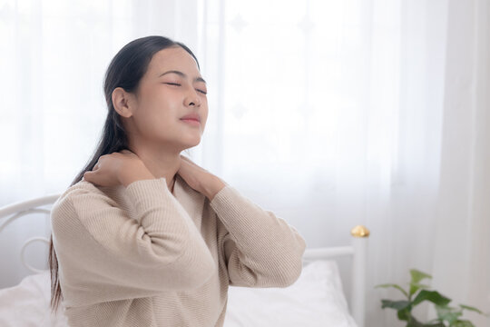 women sitting in bed touching her shoulder pain, morning muscle stiffness, neck and shoulder tension, poor posture, stress concept, healthcare, body discomfort.