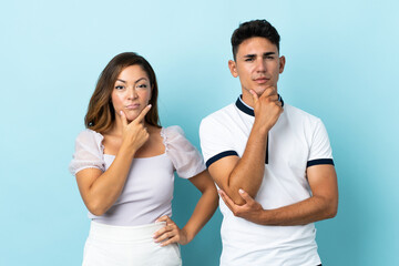 Obraz premium Young caucasian couple isolated on blue background having doubts and with confuse face expression