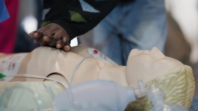 Black person practicing cpr on a medical mannequin during first aid training