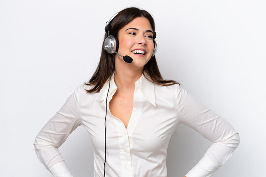 Telemarketer caucasian woman working with a headset isolated on white background posing with arms at hip and smiling