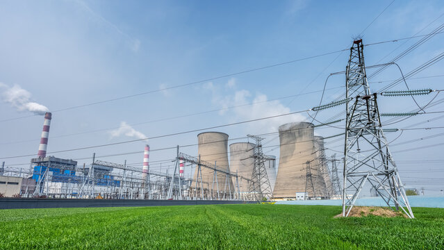 Coal-Fired Power Plant with Cooling Towers with Transmission Towers and Wheat Field in Foreground Under Blue Sky