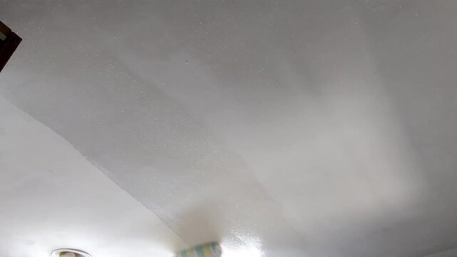 Painter hands painting ceiling with roller during renovation