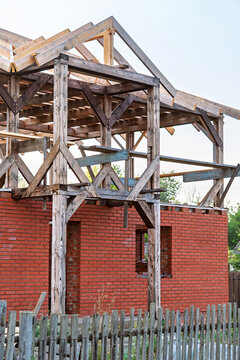 Framework of an incomplete entrance section of neglected cottage. Wooden beams are visible along with brickwork, indicating ongoing construction that has halted