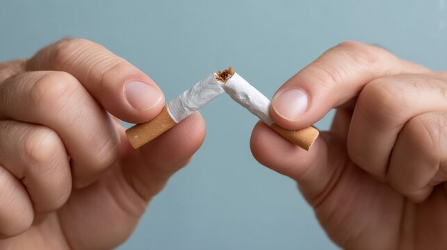 Hands Breaking Cigarette in Two Against a Neutral Background for Smoking Cessation Concept
