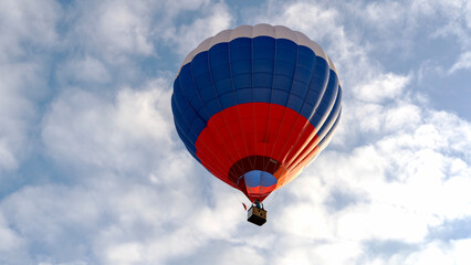Fototapeta premium Blue, red, and white balloon floats through sky