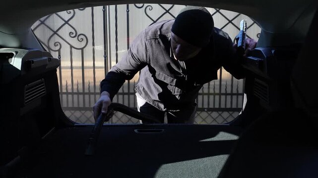 Car dry cleaning. Vacuuming the trunk of a car, removing small particles, close-up shot. Interior cleaning. A man vacuuming the trunk of a car.