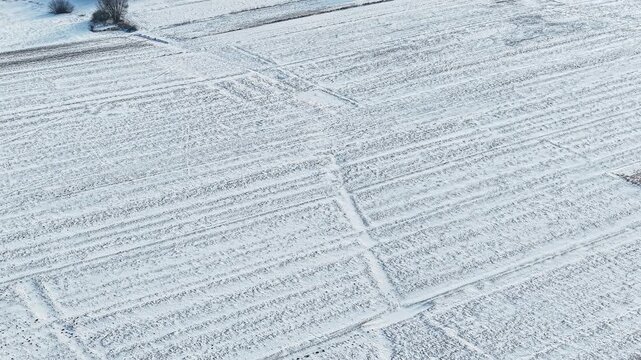 Snow covered agricultural field with tractor track patterns