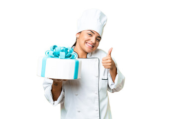 Woman pastry chef with a big cake with thumbs up because something good has happened
