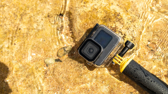 Action camera rests in clear, shallow water
