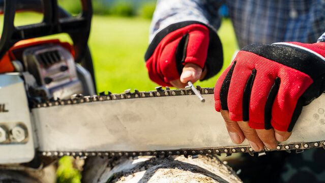 Hands adjust chainsaw chain, ready for work