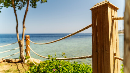 Naklejka premium Sunlit wooden posts frame a tranquil coastal path