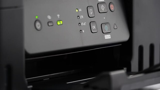 Printer control panel illuminated in close-up shot. Green indicator lights signal active status. Buttons and icons arranged clearly for user interaction. Ideal for tech support, office setup