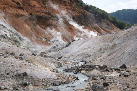 Dramatic volcanic valley with steaming vents and a winding river.