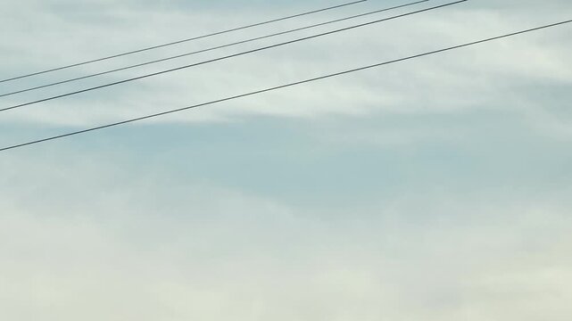 Silhouette of person ziplining against blue sky, enjoying outdoor adventure thrill