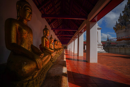 Golden Buddha statues lined up in a serene temple corridor.