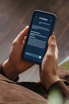 Close up of a man holding a smartphone, using an AI chatbot app for work, brainstorm a business project. Personal Artificial intelligence assistant helping with productivity. Vertical photo