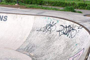 Naklejka premium Empty concrete skatepark ramp with black graffiti tags