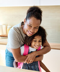 Obraz premium Mother helping daughter to get ready for school, helping her with backpack and books, and making snack sandwich in the kitchen hugging and leaving home