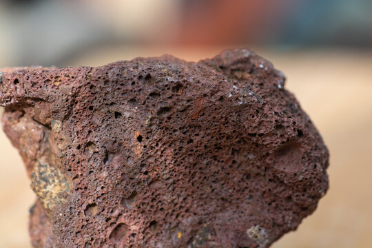 Macrophotographie d'une roche volcanique rouge poreuse (scorie).