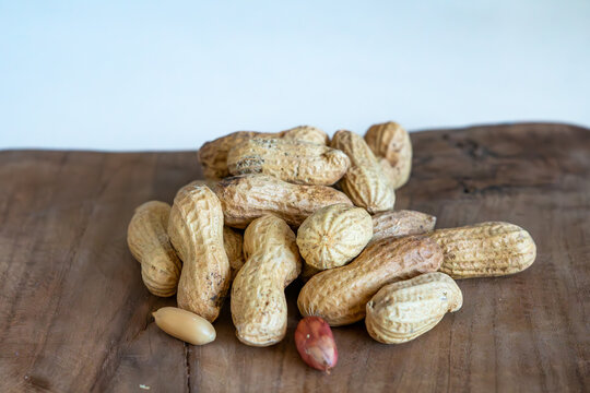 Roasted peanuts in shells on wooden table, heap of groundnuts with peeled kernels, healthy snack, natural wood background, healthy nutrition concept, arachis hypogaea close up, rustic food photography