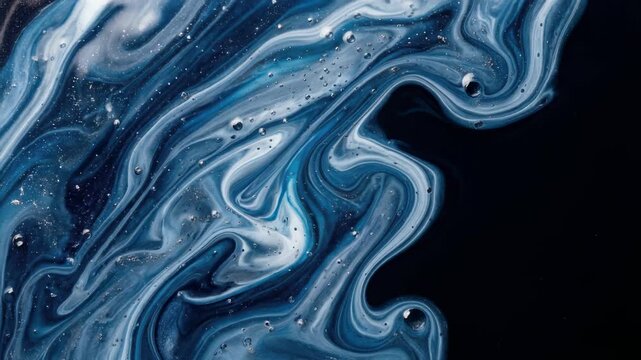 Swirling blue and white liquid paint creating an abstract marbled texture. Macro fluid art background with glitter and bubbles on a dark canvas