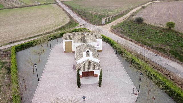 Bird's-eye view video of a church in the middle of the countryside where white predominates; its bell tower is what gives the entrance