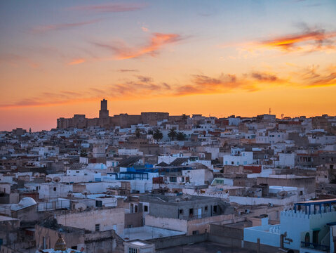 Sunset view over the historic medina of Sousse, Tunisia, with dense urban rooftops and warm evening light, evoking culture, tradition, everyday city life, and North African atmosphere