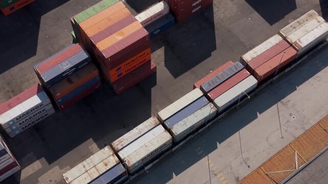 Shipping Containers Stacked at Port: An aerial view showcases a variety of colorful shipping containers neatly stacked and arranged at a bustling port, ready for global transport.