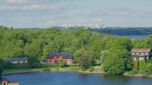 Historic wooden villa surrounded by lush green park beside tranquil waterfront