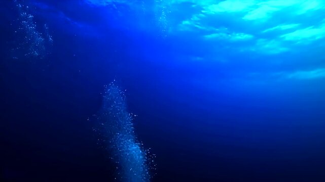 Deep blue underwater scene with sunlit surface, bubbles, and subtle cloud-like formations