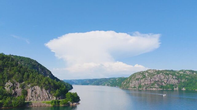Dramatic fjord landscape with towering cliffs and expansive summer cloud formation