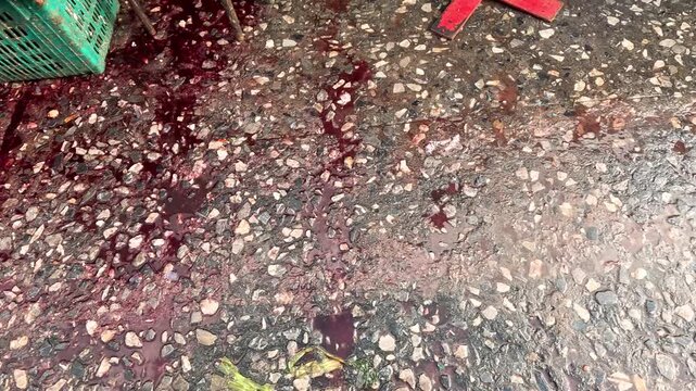 Blood stains on ground concrete floor outside market messy outdoor scene.