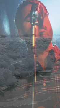 Vertical video: Singer leaning into retro mic, singing music, causing ocean overlay, silhouetting