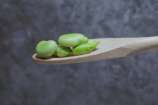 fresh broad beans, jackdaws on a wooden spoon