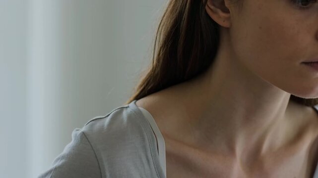 Close-up of woman adjusting shoulder strap under clothing, personal comfort and fit, everyday routine, subtle movement, indoor lifestyle, natural light