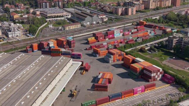 Logistics Hub: An aerial view of a bustling logistics yard filled with stacked shipping containers, with a warehouse and railway tracks visible, showcasing global trade and transportation.