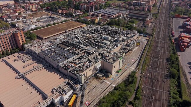 Urban Logistics Hub: An expansive industrial complex, featuring a massive warehouse and adjacent railway lines, represents a critical node in urban supply chain networks.