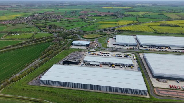 Drone shot of busy distribution warehouse with lorries loading at bays in the English Midlands
